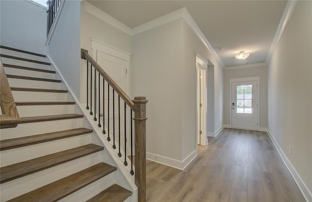 foyer featuring crown molding, stairway, baseboards, and wood finished floors