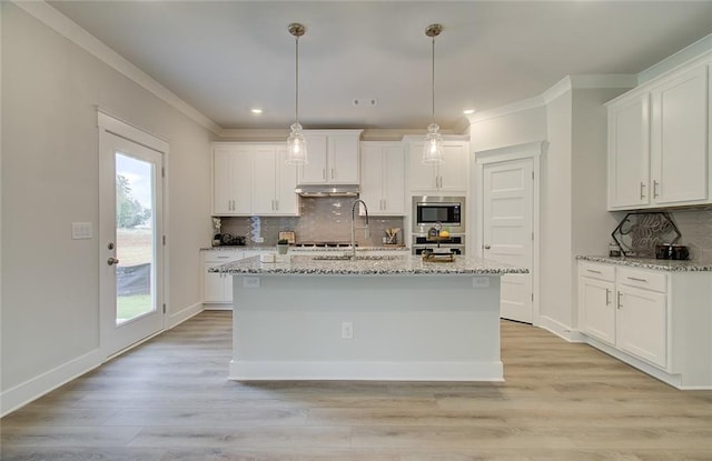 kitchen with light wood-style flooring, appliances with stainless steel finishes, white cabinetry, a sink, and under cabinet range hood