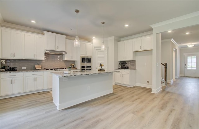 kitchen with crown molding, stainless steel appliances, white cabinets, and under cabinet range hood