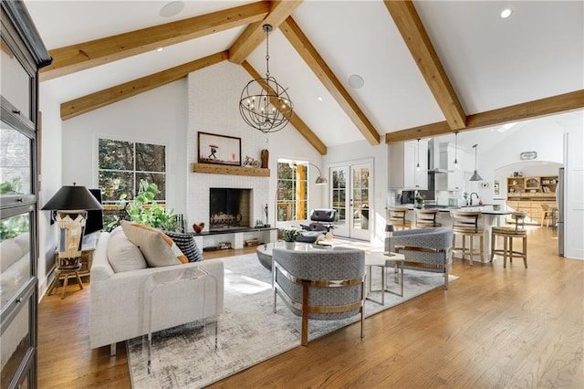 living room featuring wood-type flooring, a brick fireplace, a healthy amount of sunlight, and high vaulted ceiling