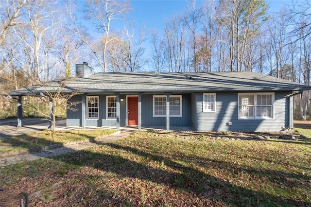 ranch-style house featuring driveway, a chimney, covered porch, a front lawn, and a carport