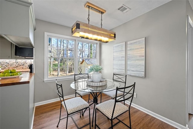 dining area featuring visible vents, baseboards, and wood finished floors