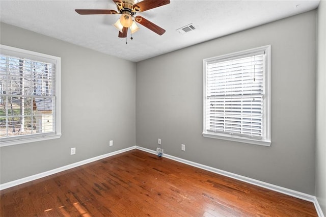 unfurnished room featuring a ceiling fan, visible vents, baseboards, and wood finished floors