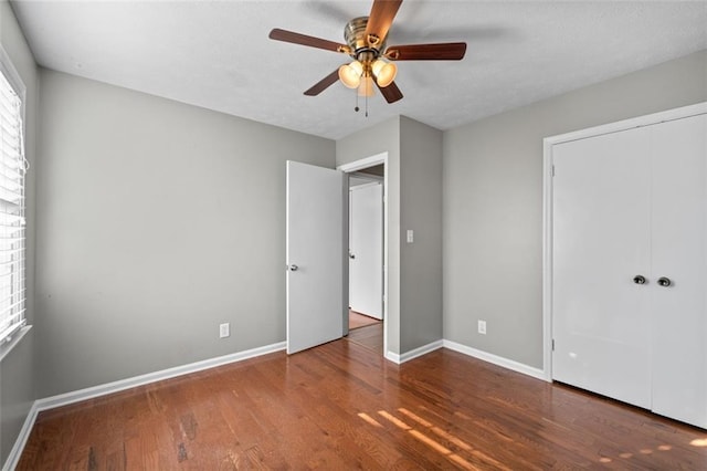 unfurnished bedroom featuring a closet, wood finished floors, a ceiling fan, and baseboards