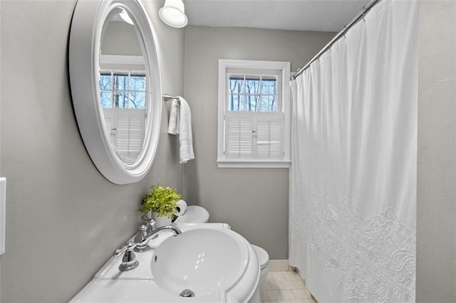 bathroom with a shower with shower curtain, baseboards, a sink, and tile patterned floors