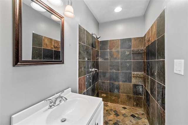 bathroom with a tile shower and vanity