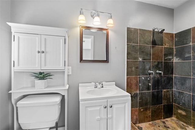 bathroom featuring a tile shower, vanity, and toilet