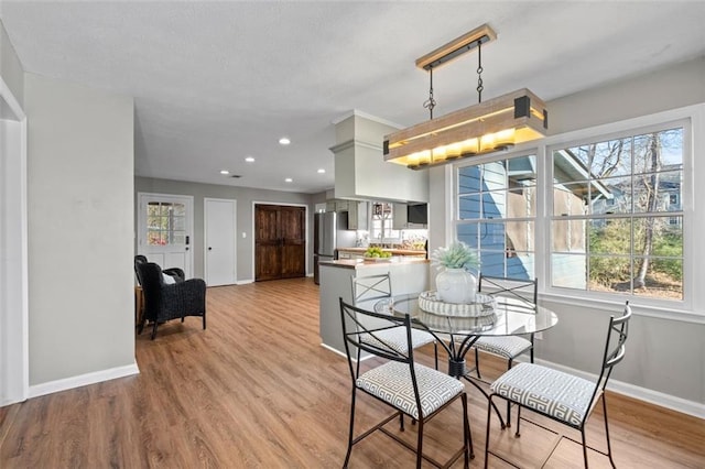 dining area with baseboards, wood finished floors, and recessed lighting