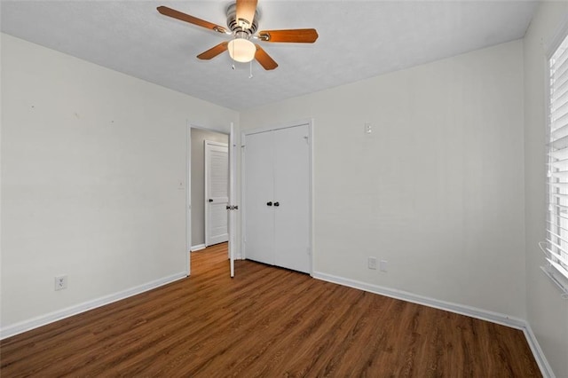 unfurnished bedroom featuring ceiling fan, a closet, wood finished floors, and baseboards