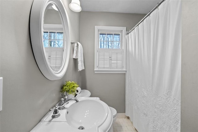 bathroom with baseboards, plenty of natural light, a sink, and tile patterned floors