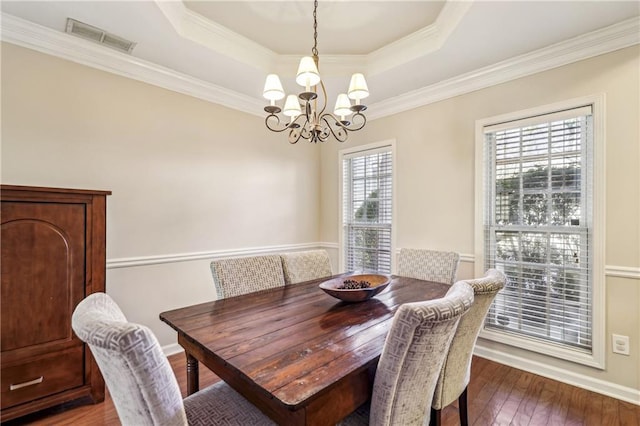 dining room featuring a raised ceiling, a chandelier, crown molding, and dark hardwood / wood-style floors