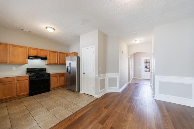 2873 Snapfinger Mnr, Decatur, GA 30035 - kitchen featuring stainless steel refrigerator with ice dispenser, black gas range oven, arched walkways, under cabinet range hood, and light countertops