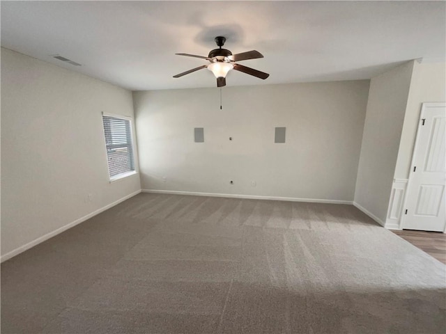 carpeted spare room with ceiling fan, visible vents, and baseboards