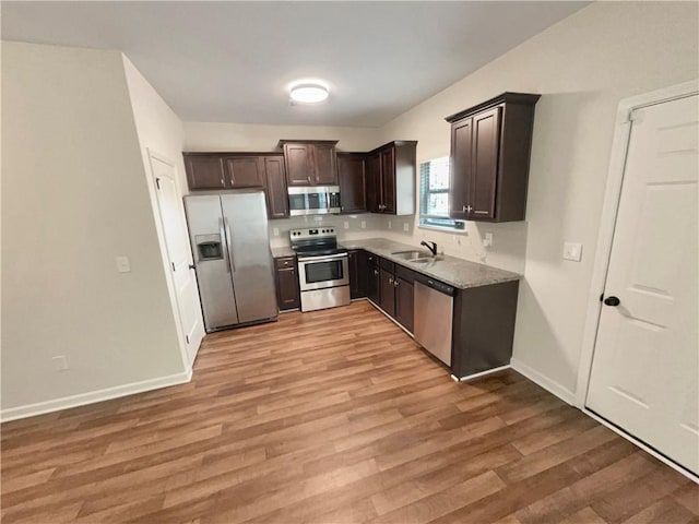 kitchen with light wood-style flooring, appliances with stainless steel finishes, dark brown cabinets, and a sink