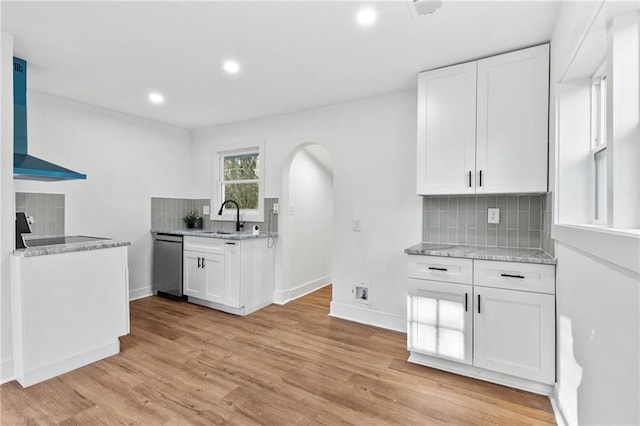 kitchen featuring dishwasher, wall chimney range hood, sink, decorative backsplash, and white cabinetry