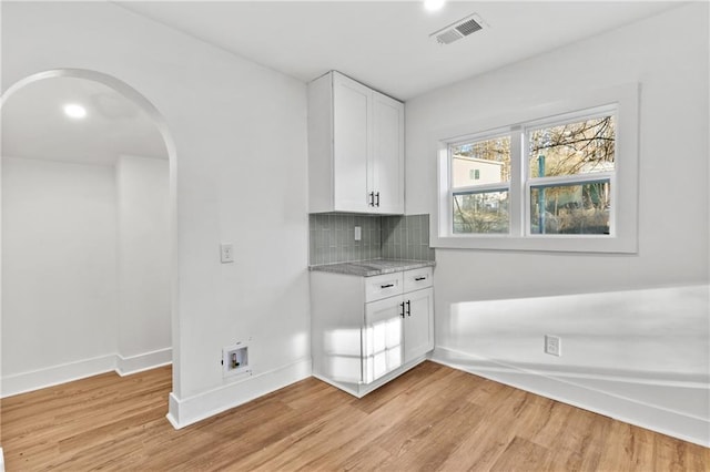 interior space with cabinets, light wood-type flooring, and hookup for a washing machine