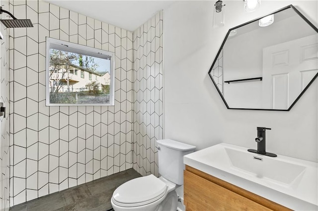 bathroom with tiled shower, vanity, and toilet