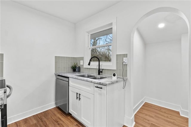 kitchen featuring dishwasher, sink, light stone countertops, light hardwood / wood-style floors, and white cabinetry