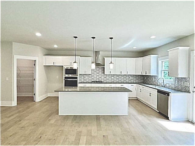 237 Lotus Ln, Covington, GA 30016 - kitchen with stainless steel appliances, wall chimney exhaust hood, a kitchen island, white cabinetry, and recessed lighting