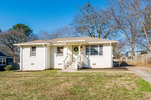 view of front of home with brick siding, a shingled roof, a front yard, crawl space, and fence