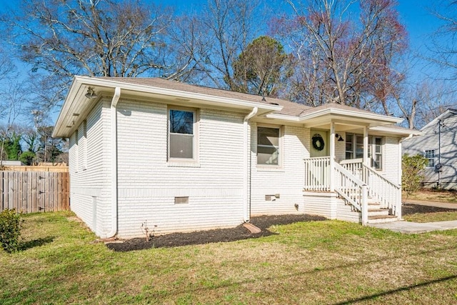 view of front of house with brick siding, crawl space, a front yard, and fence