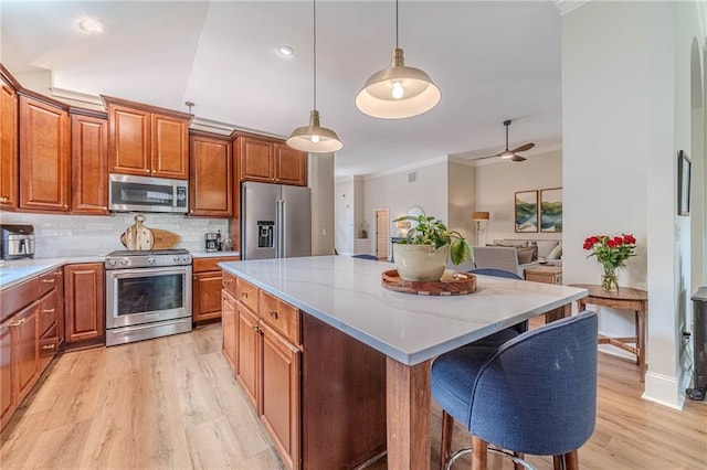 kitchen with stainless steel appliances, light wood-style flooring, brown cabinets, decorative backsplash, and ornamental molding