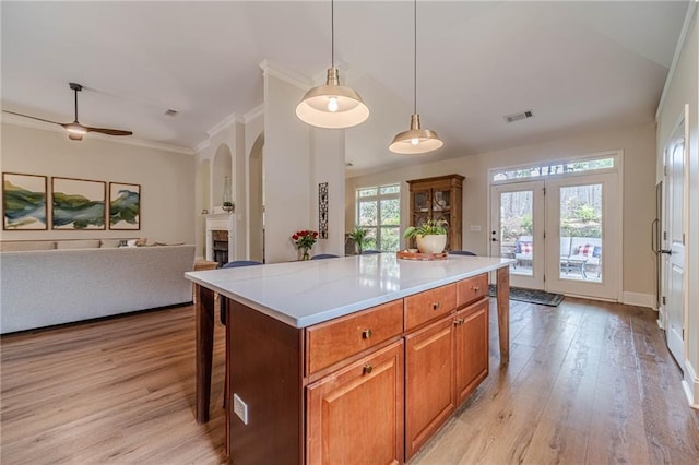 kitchen with light wood-style floors, open floor plan, light countertops, a fireplace, and brown cabinets