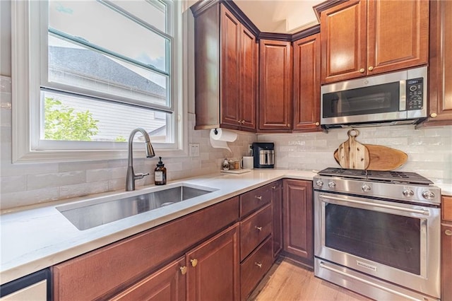 kitchen with stainless steel appliances, a sink, tasteful backsplash, and light wood-style floors