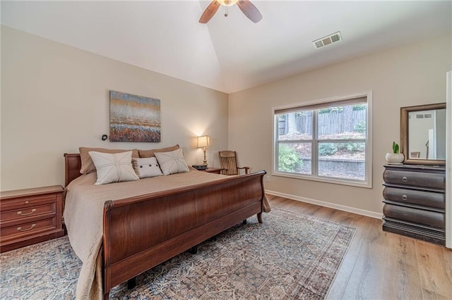 bedroom featuring light wood-style flooring, lofted ceiling, a ceiling fan, and baseboards