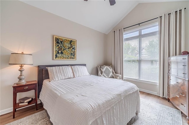 bedroom with light wood-style flooring, vaulted ceiling, baseboards, and a ceiling fan