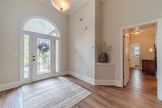 entryway with crown molding, plenty of natural light, wood finished floors, and baseboards