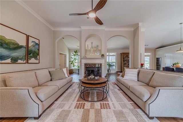 living room featuring arched walkways, crown molding, ceiling fan, and wood finished floors