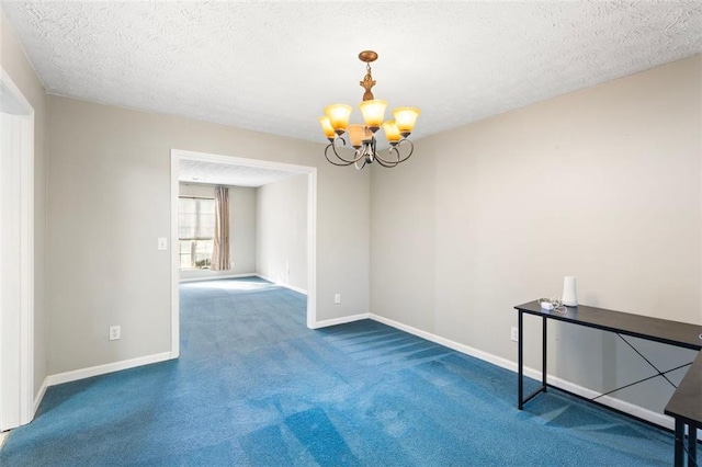 empty room featuring a chandelier, a textured ceiling, and carpet floors