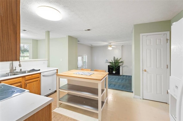 kitchen with ceiling fan, sink, white dishwasher, and a textured ceiling