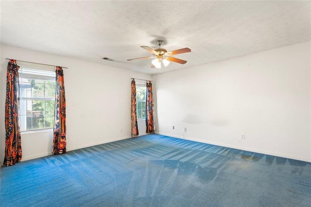 empty room featuring carpet flooring, ceiling fan, plenty of natural light, and a textured ceiling