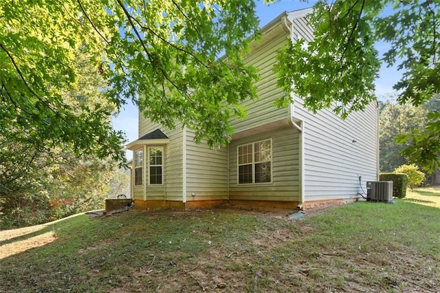 view of side of property with a lawn and cooling unit