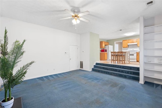 carpeted living room with built in shelves, ceiling fan, and a textured ceiling