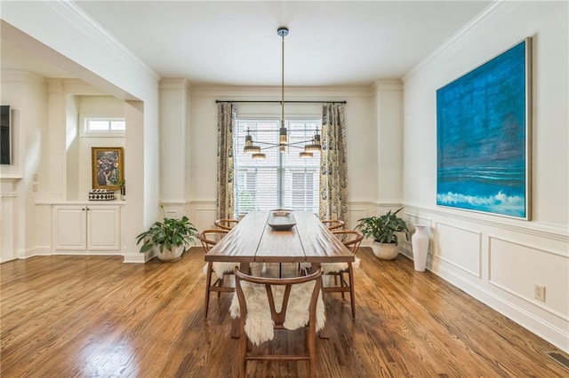 2313 Saint Davids Sq NW Unit 12, Kennesaw, GA 30152 - dining area with wood finished floors, a chandelier, a decorative wall, crown molding, and a wainscoted wall
