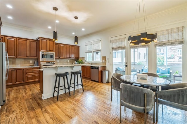 2313 Saint Davids Sq NW Unit 12, Kennesaw, GA 30152 - kitchen with appliances with stainless steel finishes, brown cabinetry, backsplash, crown molding, and a center island