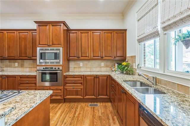 2313 Saint Davids Sq NW Unit 12, Kennesaw, GA 30152 - kitchen featuring stainless steel appliances, a sink, light wood-style flooring, brown cabinetry, and light stone countertops