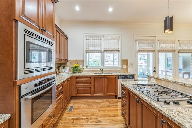 2313 Saint Davids Sq NW Unit 12, Kennesaw, GA 30152 - kitchen featuring stainless steel appliances, a sink, brown cabinetry, ornamental molding, and light stone counters