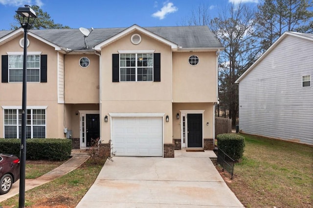 view of property featuring driveway, brick siding, an attached garage, and stucco siding