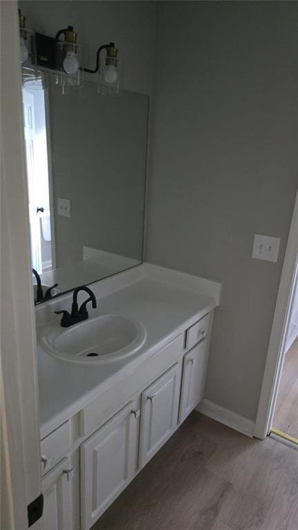 bathroom with baseboards, wood finished floors, and vanity