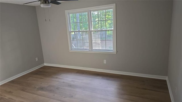 unfurnished room with wood finished floors, a ceiling fan, and baseboards