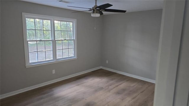 spare room with ceiling fan, plenty of natural light, baseboards, and wood finished floors