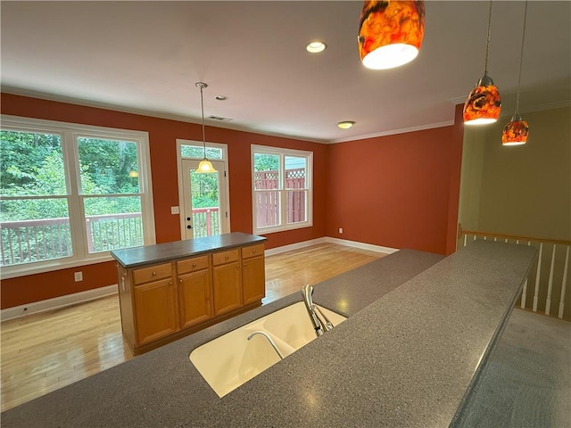 2895 Brandl Cove Ct Unit 4, Marietta, GA 30067 - kitchen with dark countertops, crown molding, light wood-style floors, a kitchen island, and decorative light fixtures