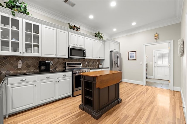 kitchen featuring white cabinetry, visible vents, stainless steel appliances, and ornamental molding