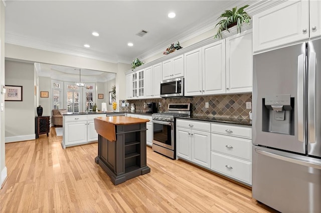 kitchen featuring a peninsula, white cabinets, stainless steel appliances, and wooden counters