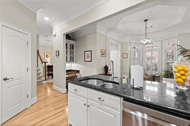 kitchen featuring light wood finished floors, stainless steel dishwasher, white cabinets, a sink, and dark stone counters