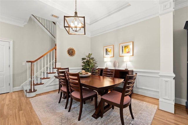 dining space featuring visible vents, light wood-style floors, stairway, decorative columns, and crown molding